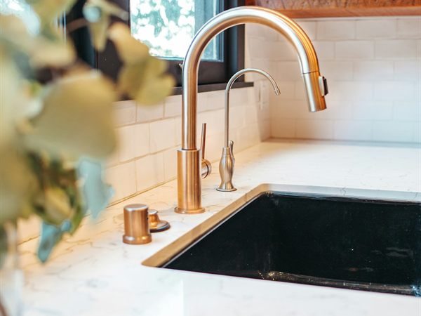 Polished stainless steel mixer tap on a white ceramic sink